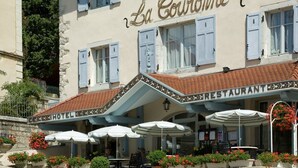 A hotel with outdoor seating and a restaurant sign. - La Couronne (Jougne)