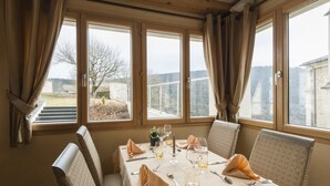 A dining table set for four with a view of the outdoors through large windows. - La Couronne (Jougne)