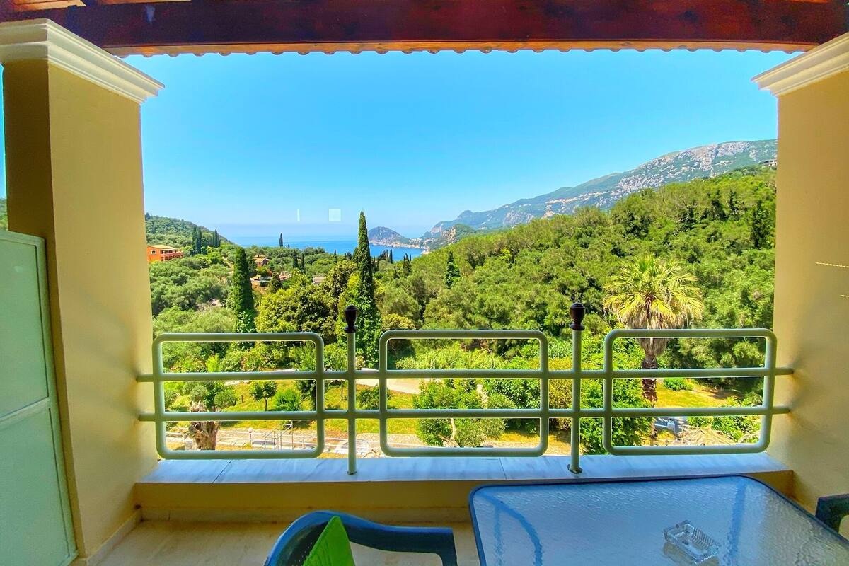 A balcony with a view of a mountainous landscape and the sea.
