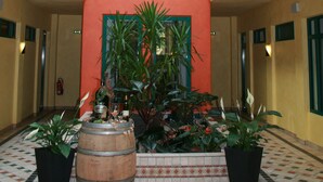 A hotel lobby with a central column, potted plants, and a tiled floor. - Weinhotel Atrium (Bad Salzuflen)