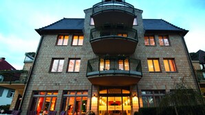 A multi-story hotel with a central atrium, balconies, and a well-lit entrance. - Weinhotel Atrium (Bad Salzuflen)