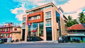 A modern building with a glass facade, a wooden section, and a sign for a massage therapy center. - Hotel Mansha Regency (Port Blair)