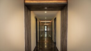 A long, narrow hallway with a polished black marble floor and wooden paneling on the walls. - Hotel Mansha Regency (Port Blair)