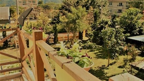 A wooden deck with a view of a garden and a building in the background. - Yishingarden B&B (Shoufeng)