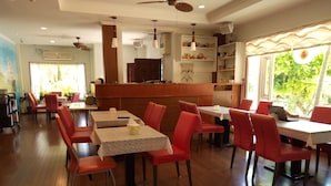 A restaurant with wooden flooring, red chairs, and tables. There is a counter with a menu and a refrigerator. - Yishingarden B&B (Shoufeng)