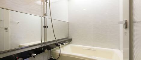 Een moderne badkamer met een bad, een douche en een grote spiegel.
