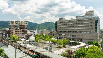 A modern urban area with a large building, a train station, and surrounding greenery.