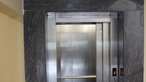 A modern elevator with a metallic finish, located in a hallway with marble walls. - White Coral (Port Blair)