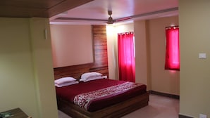 A bedroom with a wooden bed, red curtains, and a ceiling fan. - White Coral (Port Blair)