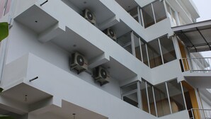 A multi-story building with balconies, air conditioning units, and a yellow accent wall. - White Coral (Port Blair)