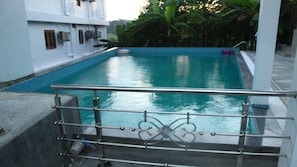 A swimming pool with a metal railing in the foreground. - White Coral (Port Blair)