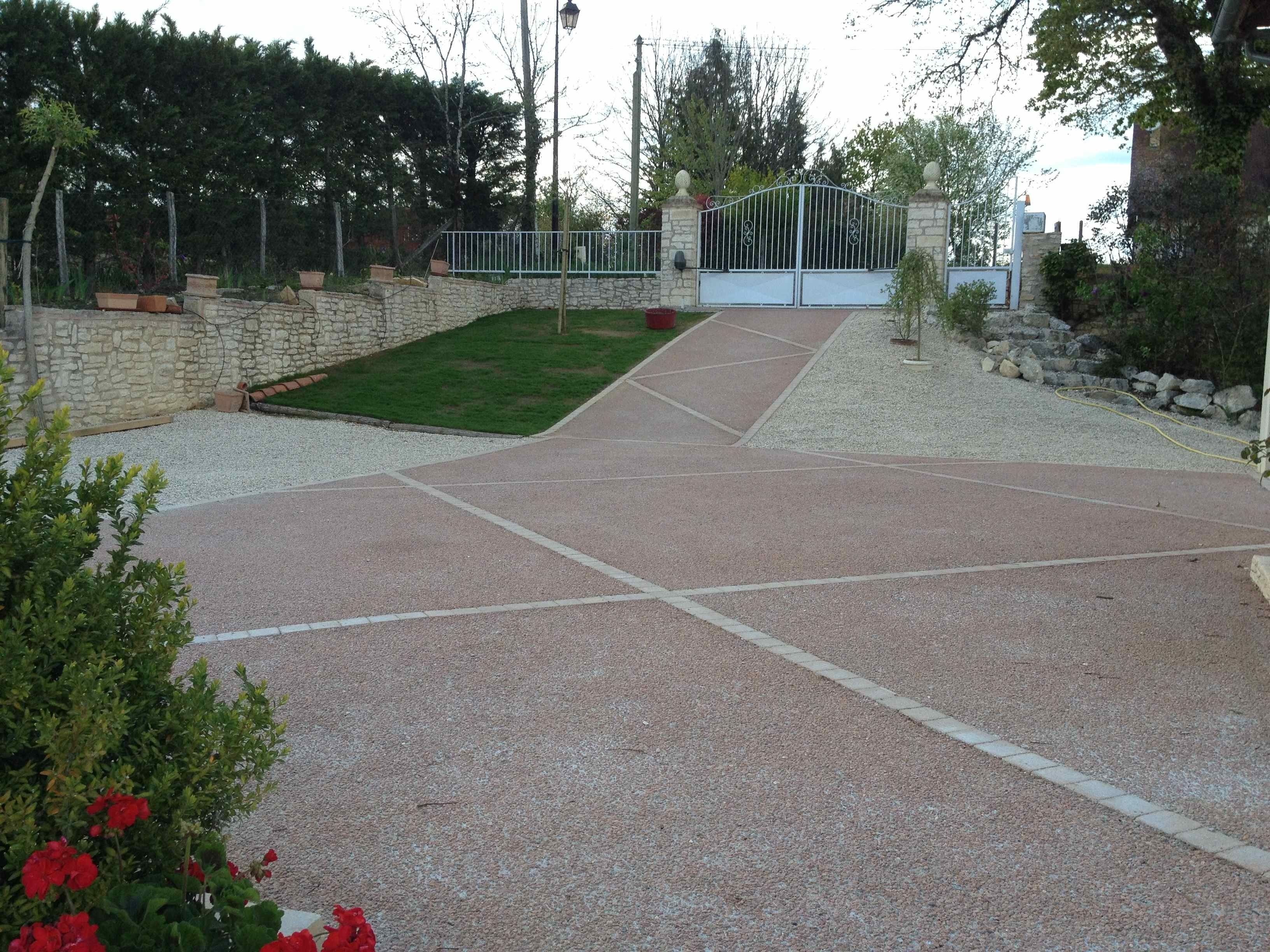 Un patio empedrado con un muro de piedra, una puerta de metal y una pequeña zona verde.