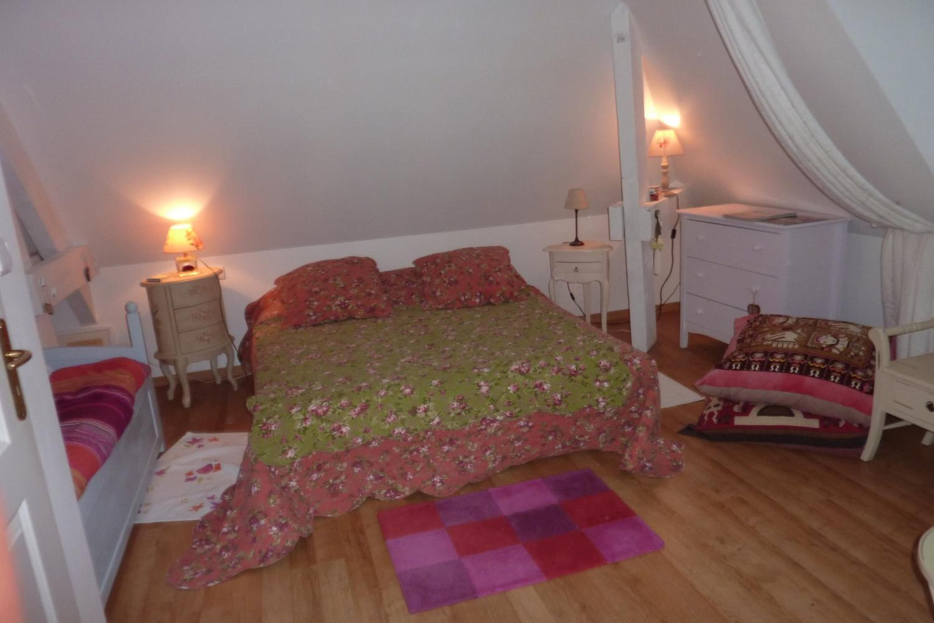A bedroom with a bed, bedside tables, a chair, and a dresser.