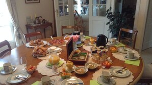 A round dining table set with various dishes, drinks, and utensils. - La Maison Du Parc (Saint-Raphaël)