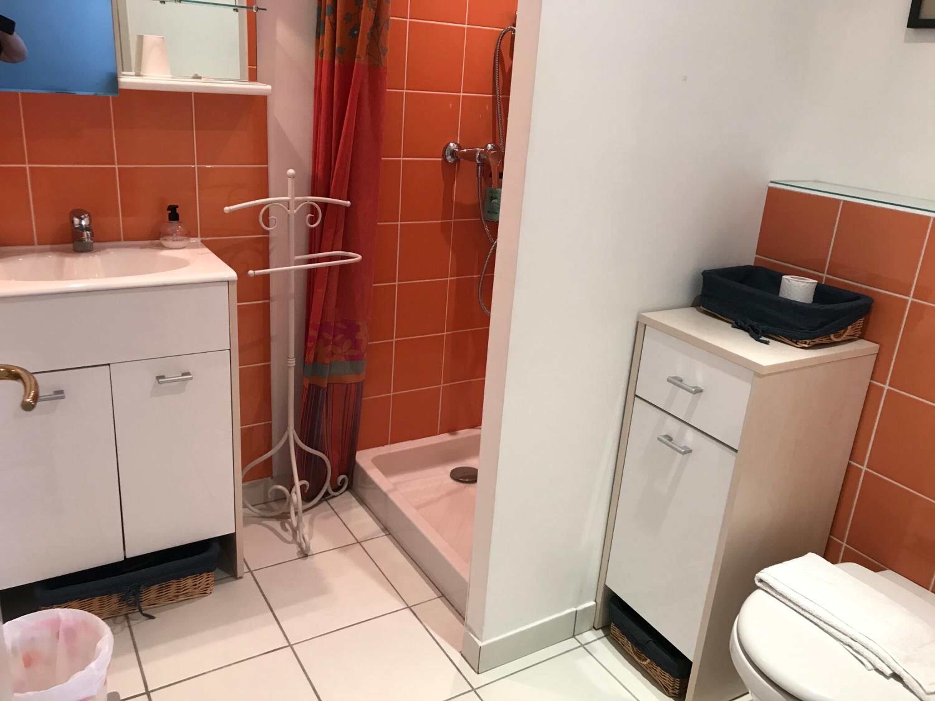 Een badkamer met een wit wastafelmeubel, toilet en douche.