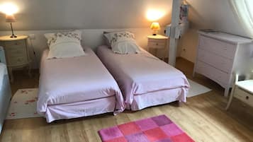 Un dormitorio con dos camas, mesitas de noche con lámparas, un aparador y una alfombra rosa y morada.