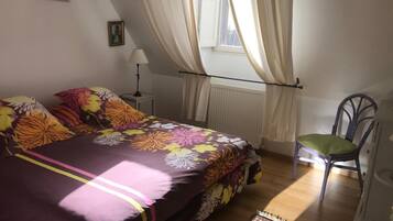 Ein Schlafzimmer mit Bett, Stuhl, Lampe und Vorhängen.