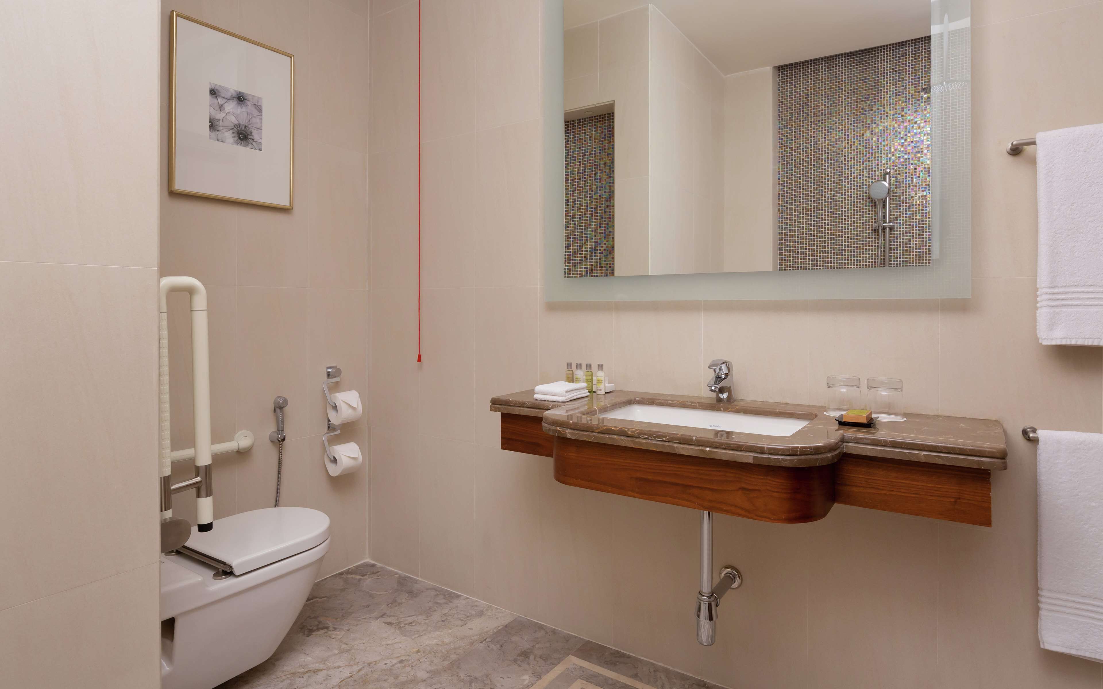A bathroom with a toilet, sink, and mirror.