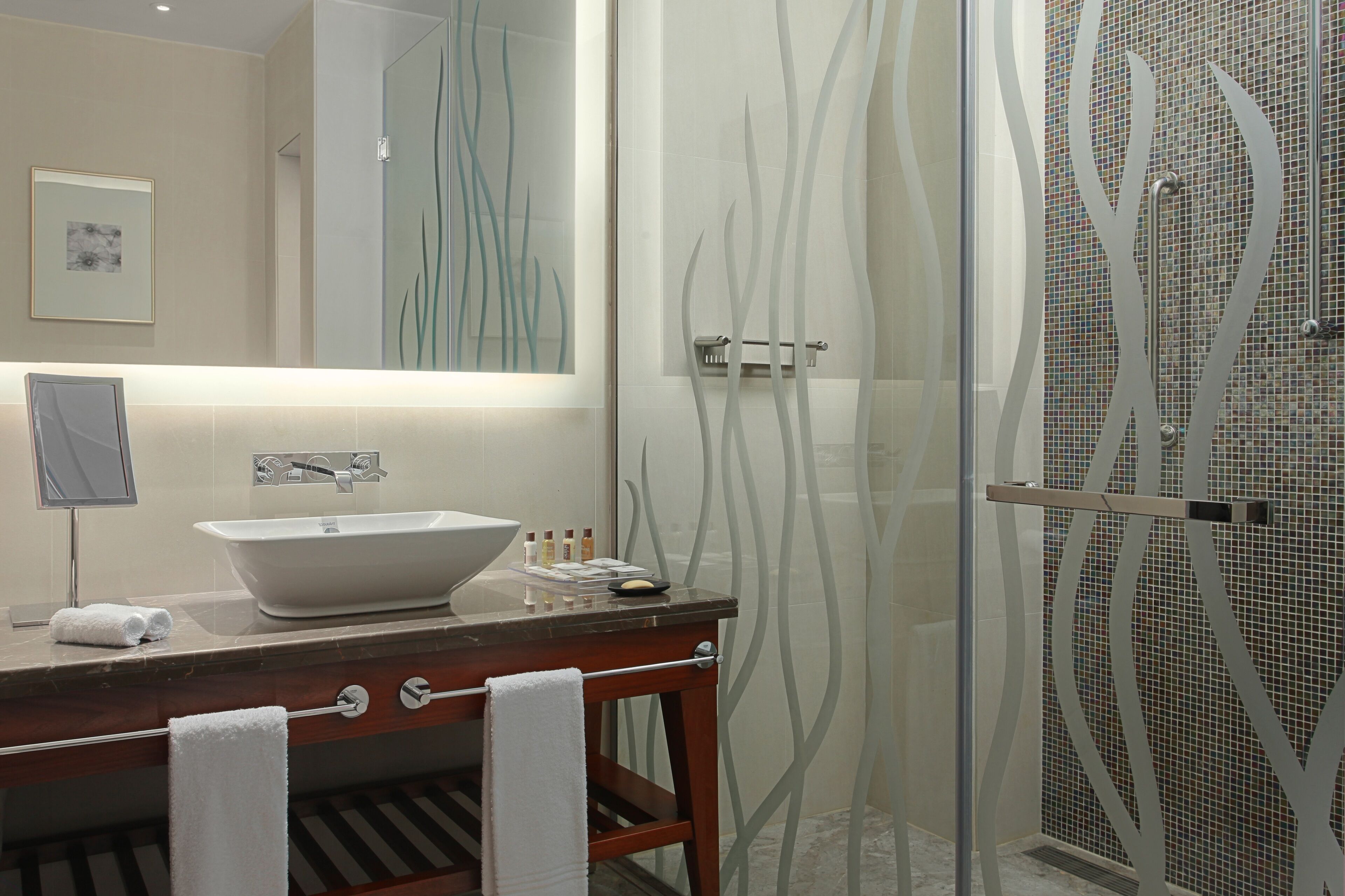 A modern bathroom with a large mirror, a vessel sink, and a glass shower enclosure.