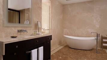 A modern bathroom with a large bathtub, a vanity with a mirror, and a dark-colored cabinet.