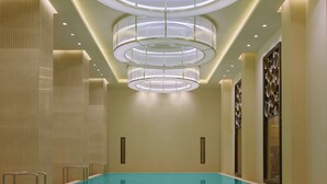 Una piscina interna moderna con fondo in vetro, illuminazione a incasso e pannelli decorativi.