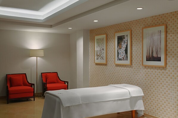 A room with a reception desk, two red armchairs, a white table with a white tablecloth, and three framed pictures on the wall.