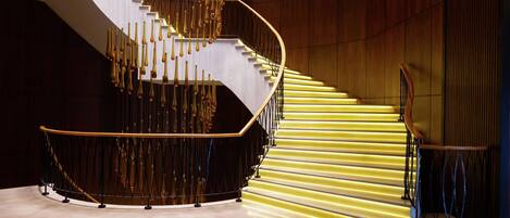 A spiral staircase with a wooden finish and illuminated steps.