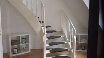 Eine weiße Treppe mit dunklen Stufen, die zu einer Empore führt.