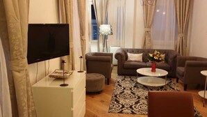Una sala de estar con un sofá, un reposapiés, una mesa de centro y un televisor.