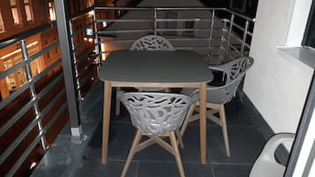 Ein kleiner, abgeschlossener Balkon mit Tisch und Stühlen, Metallgeländern und Blick auf die Straße.