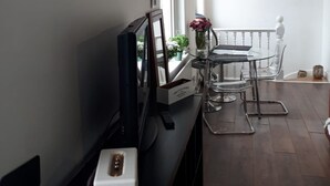 A room with a TV, a small table with a vase, and a chair. - The Portobello Loft (London)