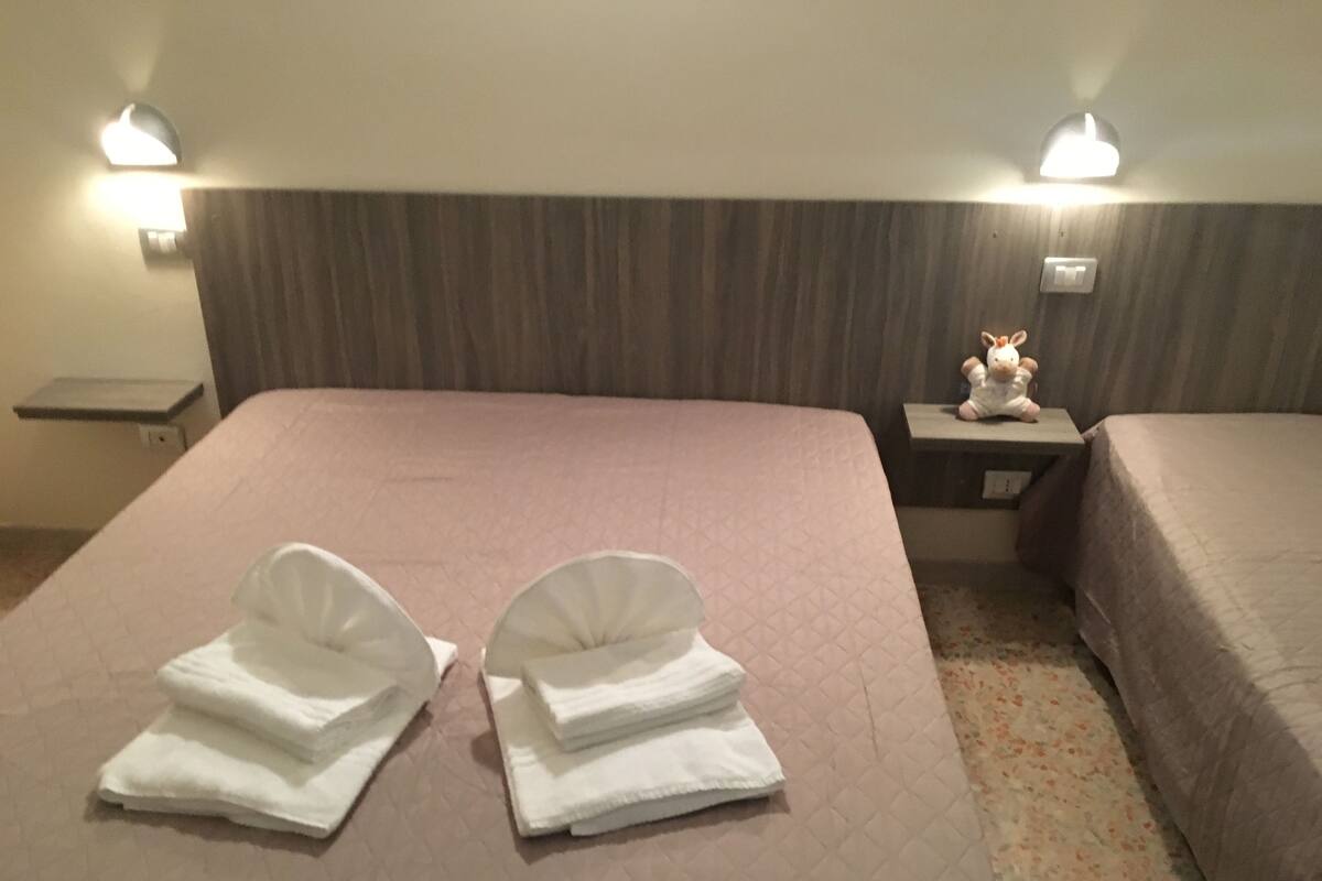 A hotel room with a large bed, two bedside tables, and a nightstand with a lamp.