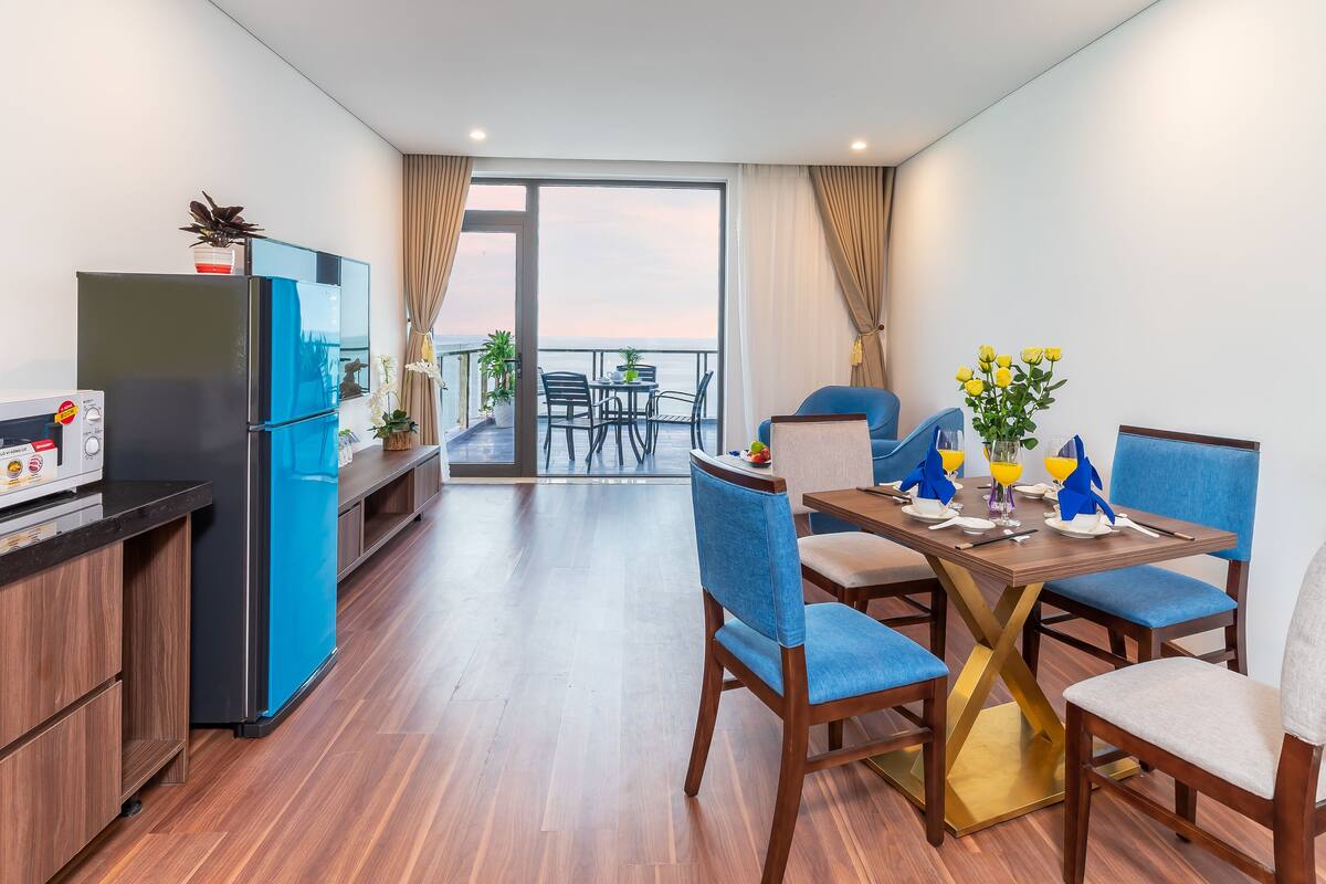 Eine moderne Küche mit Kühlschrank, Mikrowelle und einem Essbereich mit blauen Stühlen und einem Holztisch.