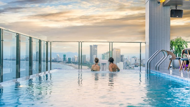 Une piscine à débordement située sur le toit, offrant une vue sur la ville, avec des garde-corps en verre et un design moderne.