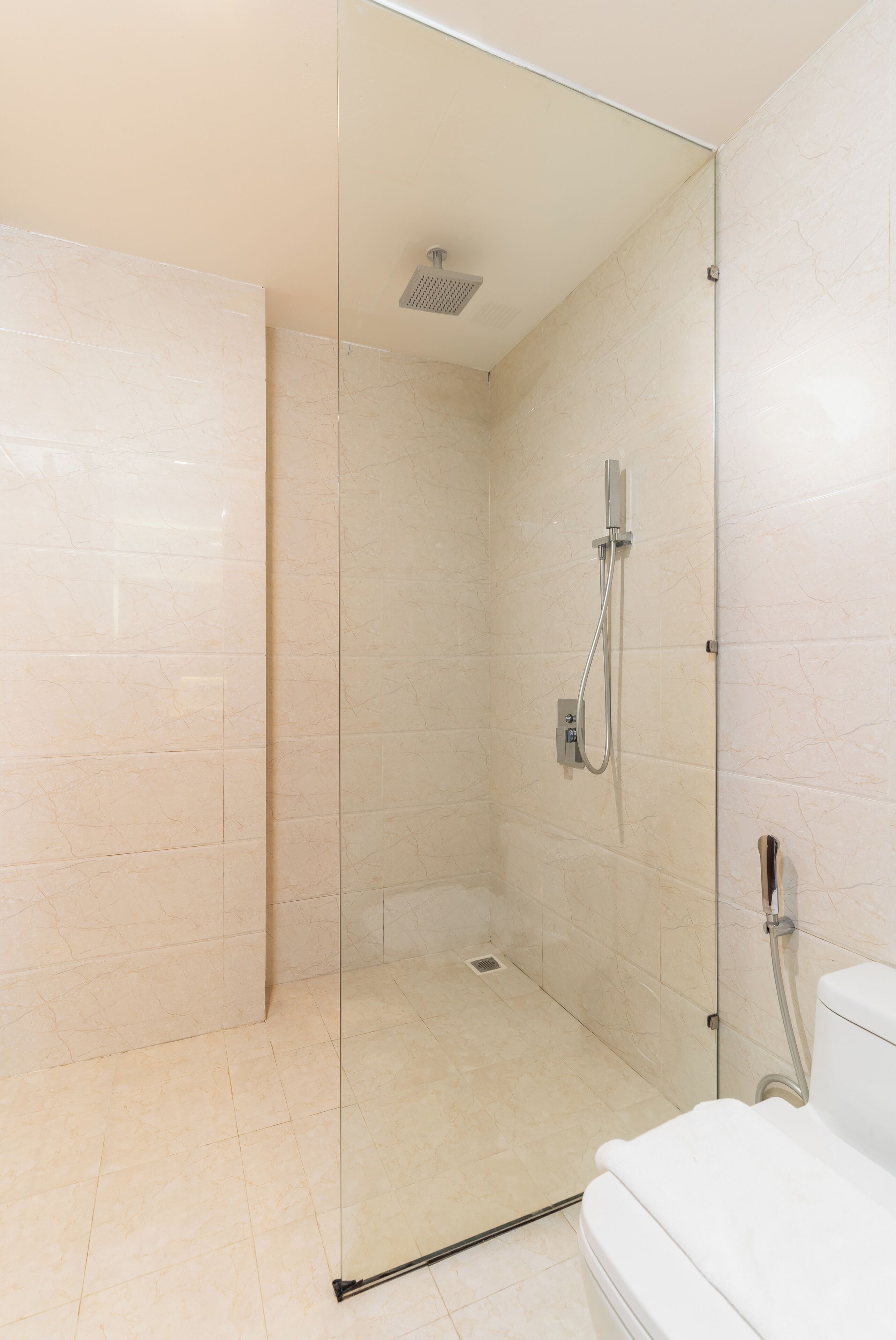 Une salle de bain moderne dotée d’une douche à parois de verre, de toilettes et d’un lavabo.
