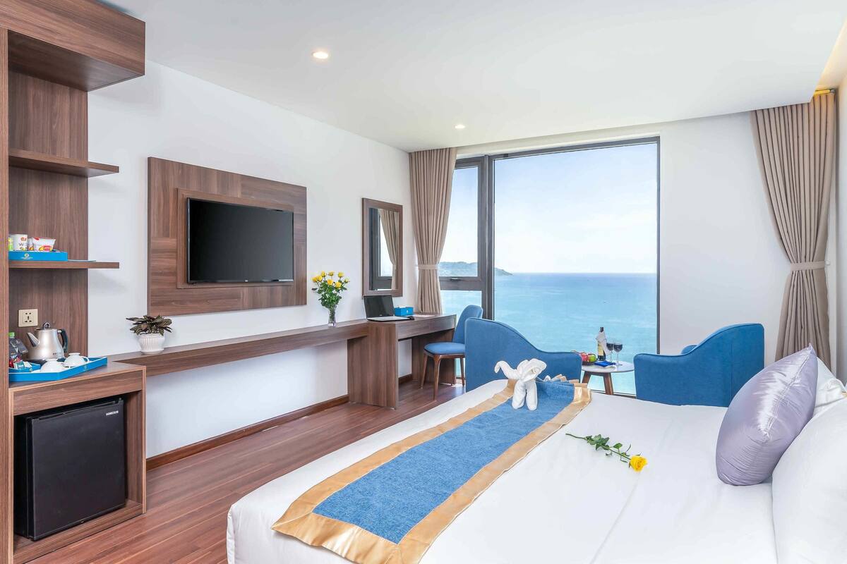 Ein modernes Hotelzimmer mit Bett, Schreibtisch, Fernseher und Meerblick.