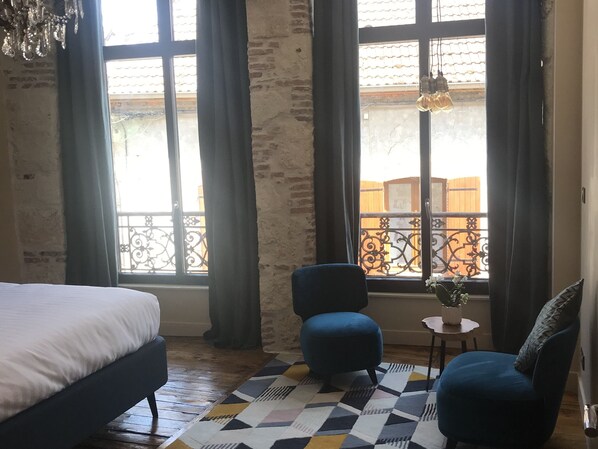 A bedroom with a bed, two chairs, a small table with a plant, and a patterned rug. - Demeure Saint Martin (Blancs-Coteaux)
