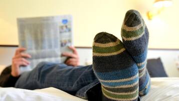 Une personne allongée sur un lit, lisant un livre, et portant des chaussettes à rayures.