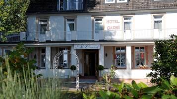 Un edificio a due piani con un balcone al piano superiore, una insegna che riporta “HOTEL GARNI” e una insegna per “Hotel Amersbrück” al piano terra.