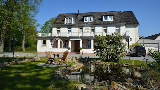 Un hôtel à deux étages doté d’un balcon, d’un étang et d’un espace extérieur aménagé pour s’asseoir.