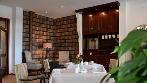 Un coin repas avec une table dressée pour quatre personnes, entourée de chaises, d’une bibliothèque et d’une lampe.