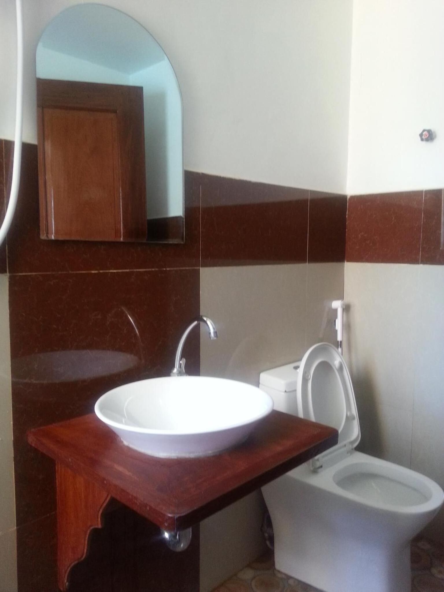 Un baño con un lavamanos blanco, un inodoro y un mueble de tocador de madera.