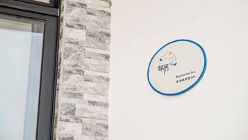 Schild des Destination Inn mit Logo und Adresse an einer weißen Wand.