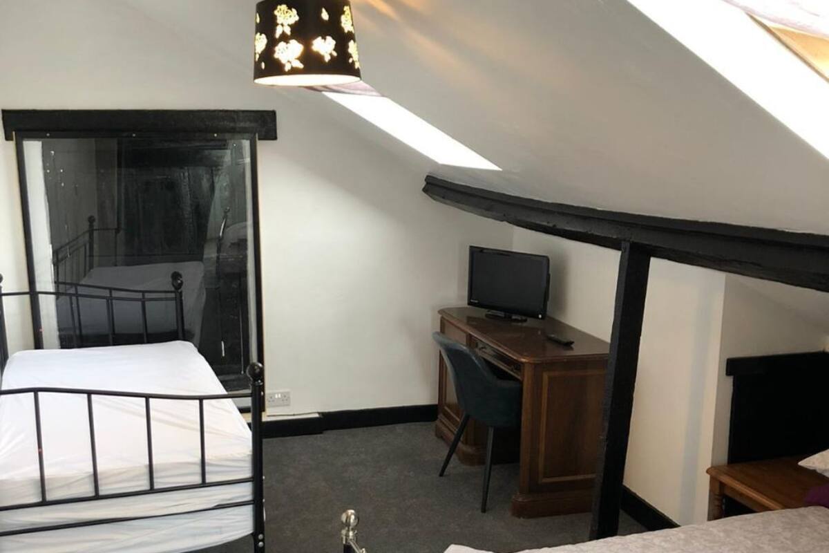 A room with a bed, a desk, a chair, a television, and a skylight.
