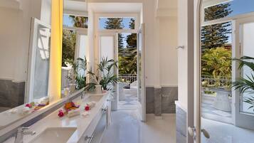 A modern bathroom with a large mirror, two sinks, and a walk-in shower.