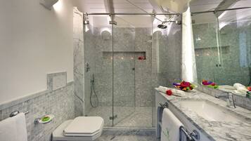 Un baño moderno con cabina de ducha de vidrio, lavamanos de mármol y un inodoro.