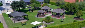 Un espace extérieur aménagé avec plusieurs kiosques, un coin salon couvert et une pelouse bien entretenue.
