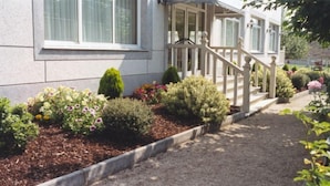 Il s’agit d’une propriété résidentielle dotée d’un jardin bien entretenu, d’un escalier en bois et d’un chemin menant à l’entrée.