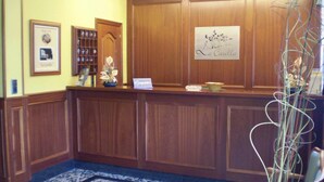 Un espace d’accueil avec un lambris en bois, un comptoir d’accueil, une photo encadrée, une vitrine et une enseigne indiquant « La Casilla ».