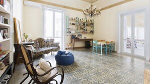 A spacious living room with a patterned floor, a bookshelf, a dining area, and a large window. - Artisan Maison (Palermo)